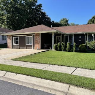 A charming single-story house with well-maintained landscaping and a paved driveway.