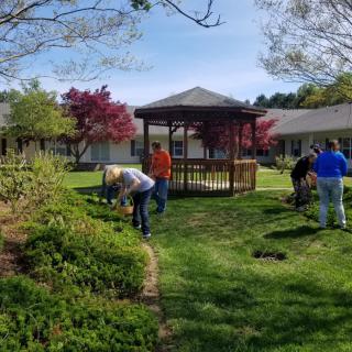 A group of people gardening near a gazebo in a park setting.