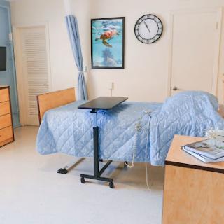 A well-organized and clean hospital patient room featuring a bed, medical equipment, and decorative artwork.
