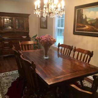 A classic dining room with a wooden table, chairs, chandelier, and a vase of flowers.