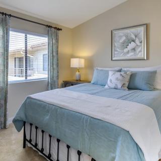 A cozy bedroom with a neatly made bed, light blue accents, and a window allowing natural light.