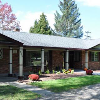 A charming single-story brick house surrounded by a well-maintained front yard and greenery.