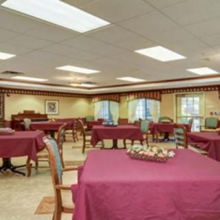 An indoor dining area with tables covered in burgundy tablecloths and wooden chairs.