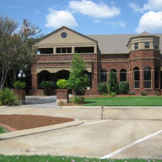 A charming brick building surrounded by greenery under a partly cloudy sky.