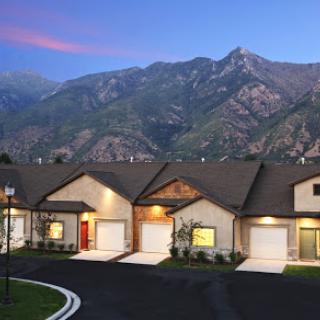 A row of modern homes set against a stunning mountain backdrop during the evening.