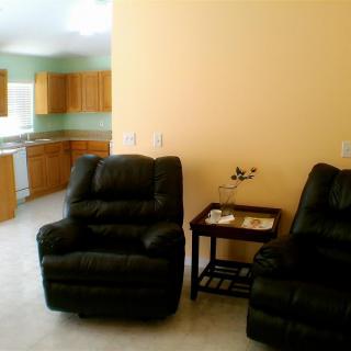 A cozy living room with recliner chairs and a view into the kitchen area.