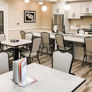 A modern dining area with tables and chairs, adjacent to a kitchen.