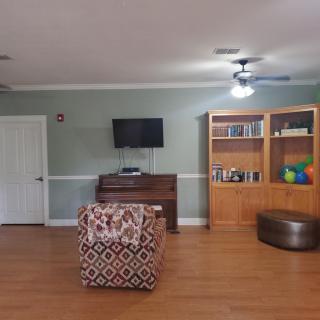 A cozy living room with a TV, bookshelf, and armchair.