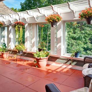 A sunny patio with a pergola adorned with hanging plants and outdoor seating.