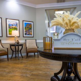 A cozy and elegantly decorated lobby area with seating, artwork on the walls, and a central table adorned with a decorative piece.