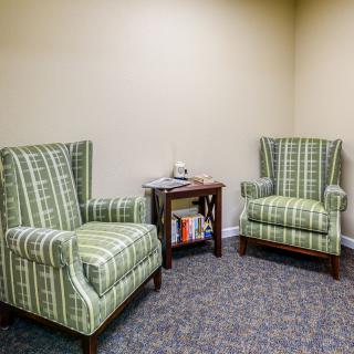 A cozy seating area with two patterned armchairs and a small table with magazines.