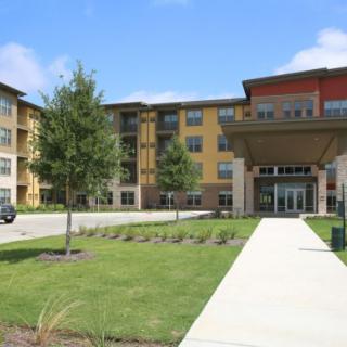 A modern residential building with a landscaped entrance and well-maintained lawn.