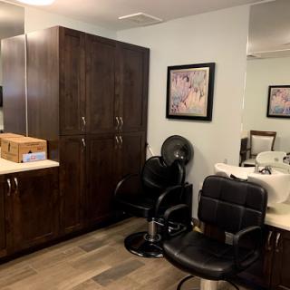 A cozy salon interior featuring stylish chairs, wooden cabinets, and artistic decor.