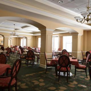 An elegant dining room with neatly arranged tables and chairs under decorative chandeliers.