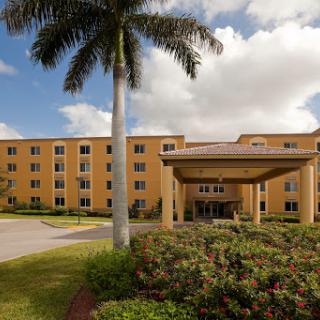 A welcoming hotel entrance surrounded by lush landscaping and palm trees.