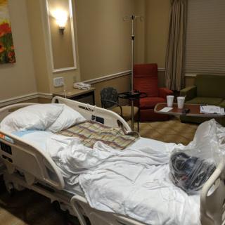 A view of a patient room in a hospital, featuring a hospital bed and seating area.