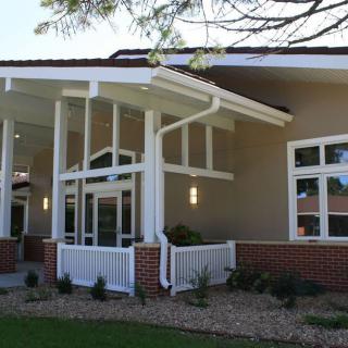 Modern building exterior with large windows and landscaped entrance.
