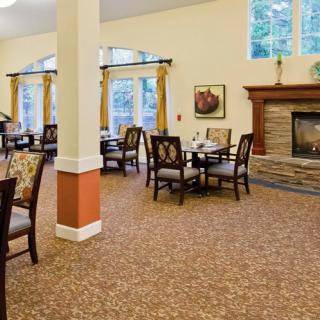 A cozy dining area with a fireplace, featuring tables and chairs, surrounded by large windows.