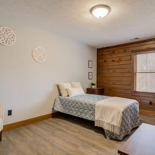 A minimalist bedroom featuring a single bed with wood paneling and neutral decor.