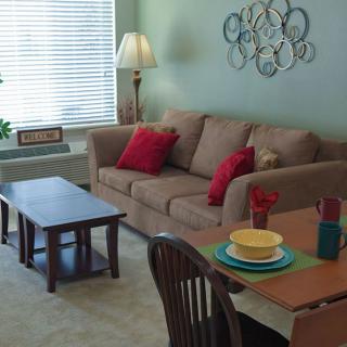 A cozy living room with a sofa, coffee table, and dining area.