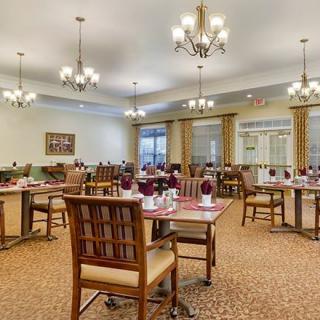 A spacious dining area with elegantly set tables and chandeliers.