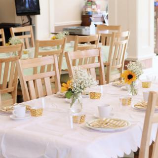 A beautifully set dining table with white tablecloths, floral centerpieces, and wooden chairs.