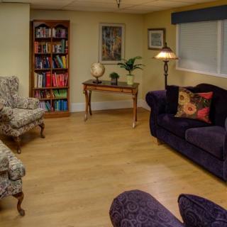 A cozy living room with a bookshelf, plush seating, and decorative elements.
