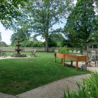 A serene garden with a fountain, surrounded by mature trees and outdoor seating.