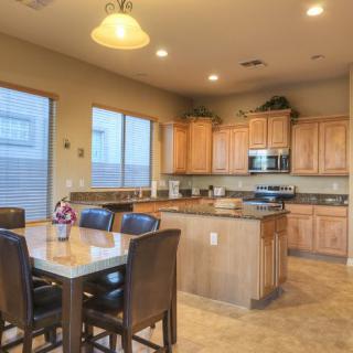 A spacious kitchen with wooden cabinets, a dining table, and modern appliances.