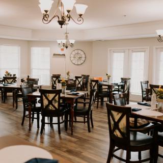 An elegantly decorated dining room featuring multiple tables and chairs set under a chandelier.