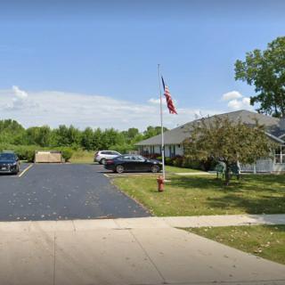 A single-story building with a parking lot, several cars, and a flagpole in front.