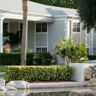 A well-maintained residential home with a garden and palm trees in front.
