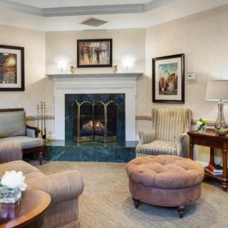 A cozy living room with a fireplace, armchairs, and an ottoman.