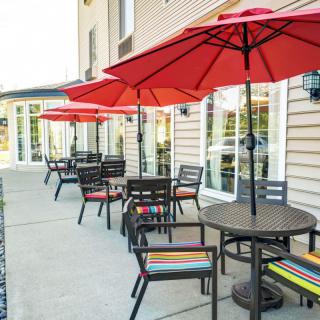 An inviting outdoor patio with red umbrellas and neatly arranged tables and chairs.