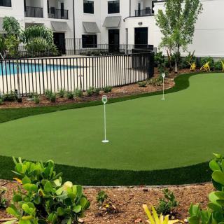 An apartment complex featuring a well-maintained putting green and swimming pool in the outdoor area.