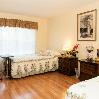 A cozy, well-lit bedroom with two beds and hardwood flooring.