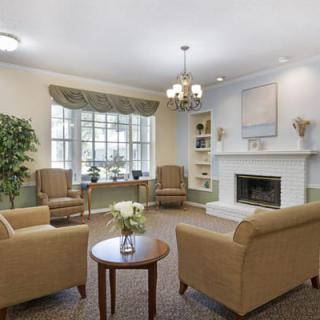 A cozy living room with a fireplace, comfortable seating, and large windows.