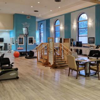 A spacious rehabilitation room equipped with exercise machines and therapy stations.