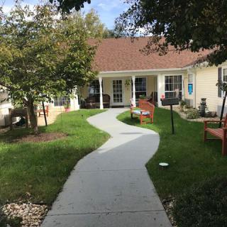 A quaint house with a winding pathway surrounded by a well-maintained lawn and garden.