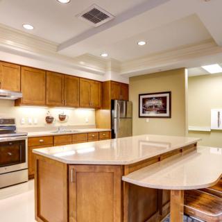 A modern kitchen with wooden cabinets, a central island, and stainless steel appliances.