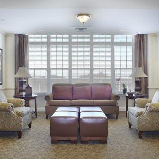 A cozy living room with a large sofa, armchairs, and coffee tables in front of a window.