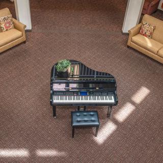 A grand piano in a spacious living room with carpet and sofas.