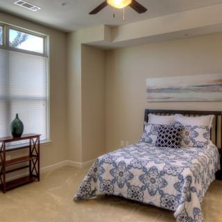 A cozy bedroom with a neatly made bed and a window allowing natural light.