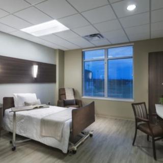 A well-lit, modern hospital room with a bed, chair, and window.