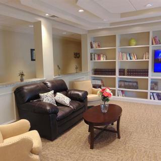 A cozy living room with a sofa, armchairs, and a bookshelf.