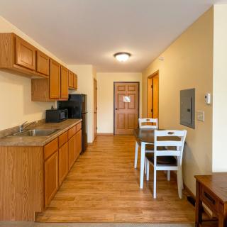 A modern apartment kitchen with wooden flooring and a small dining area.
