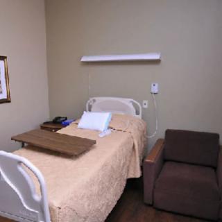A hospital room with a single bed and chair.