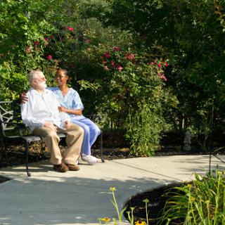 A caregiver and an elderly person enjoying a peaceful moment together in a garden.