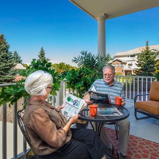 A senior couple enjoying coffee and reading on a porch.