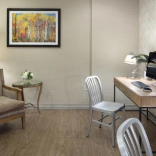 A tidy and modern office space with a desk, chair, computer, and artwork on the wall.